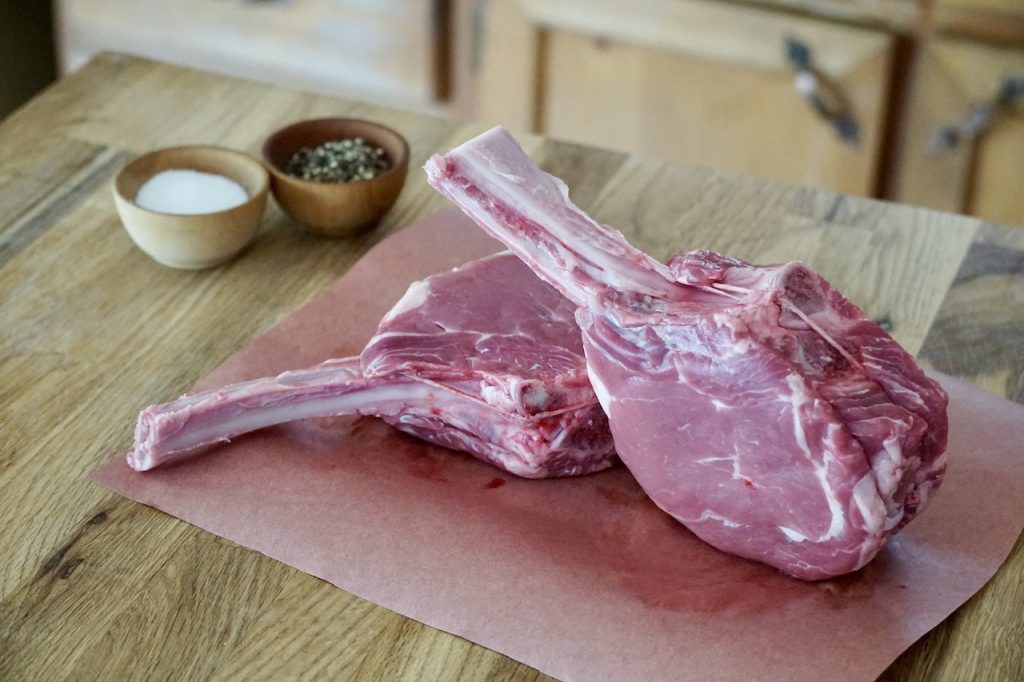 Two Frenched veal rib chops displayed on a sheet of butcher paper.