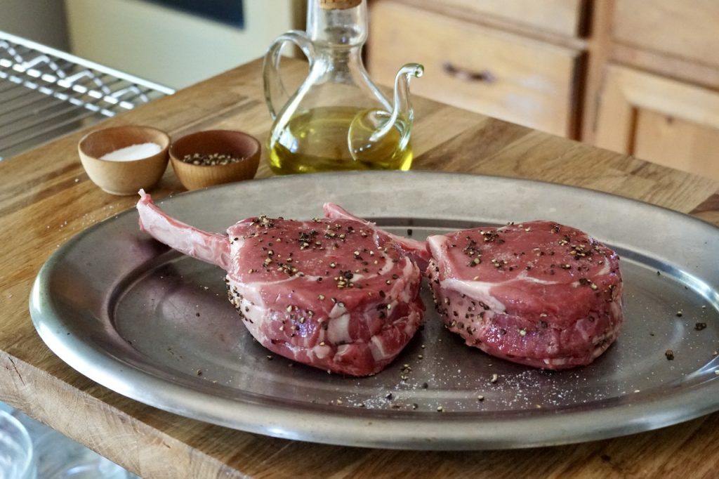 Two veal rib chops prepared with a drizzle of oil, salt and pepper.
