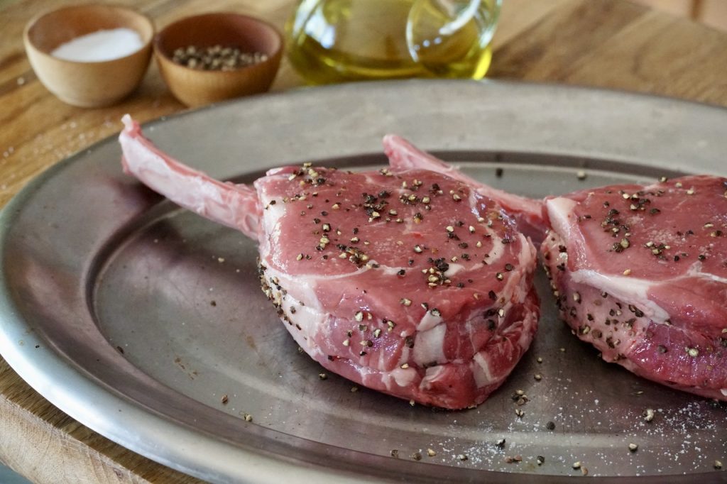 A close up of the seasoned veal rib chop ready to be grilled.