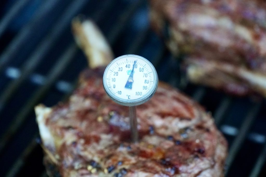 A probe thermometer inserted into a grilled veal rib chop.