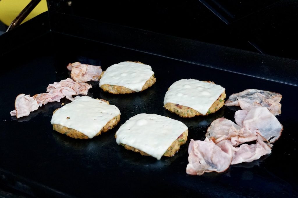 Portions of shaved ham and the cooked burger patties topped with melted Swiss cheese.