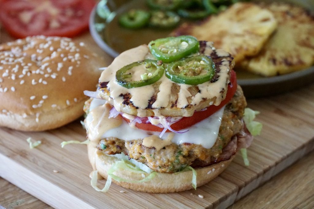 The Grilled Hawaiian Chicken Burgers assembled, stacked on hamburger buns.