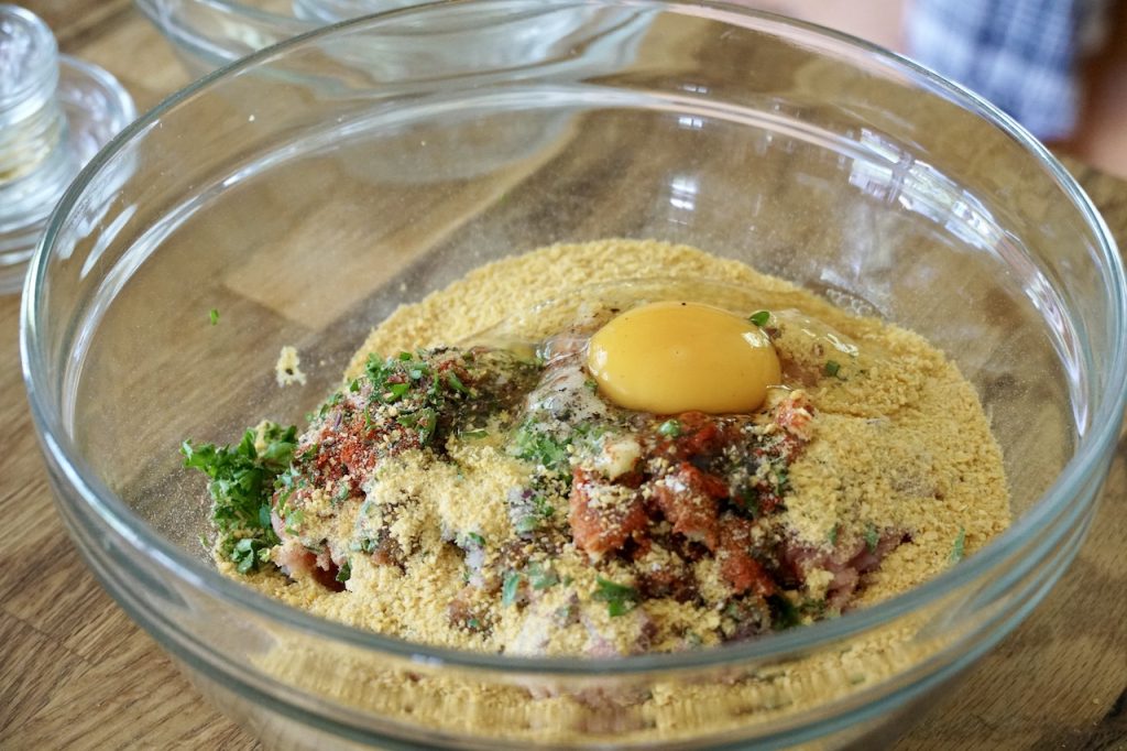 The ingredients for the chicken burgers assembled in a large bowl, ready to be combined by hand.