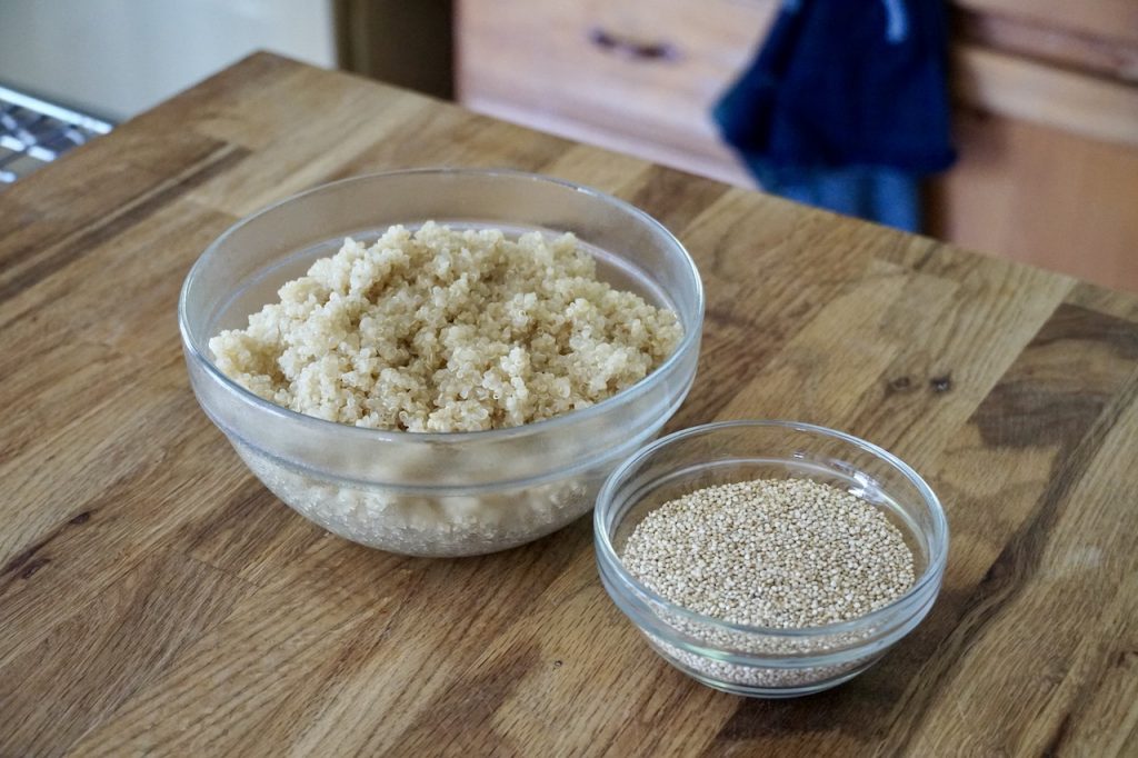 Bowls of cooked quinoa and uncooked quinoa.