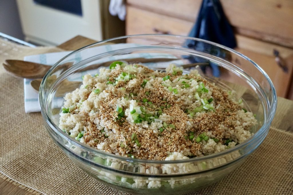 A large bowl of spinach with assorted vegetables and quinoa.