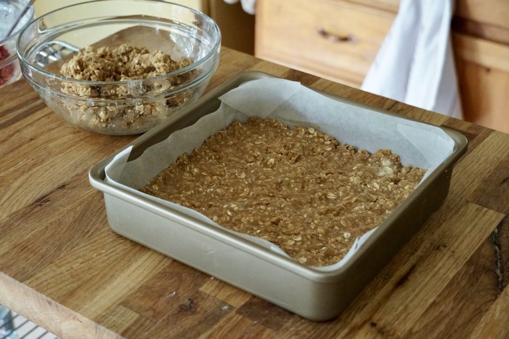 A square metal baking pan with the pastry base for the squares pushed down into the bottom of the pan.