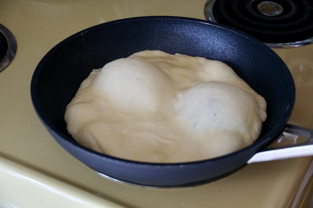 One flatbread cooking in a large skillet.