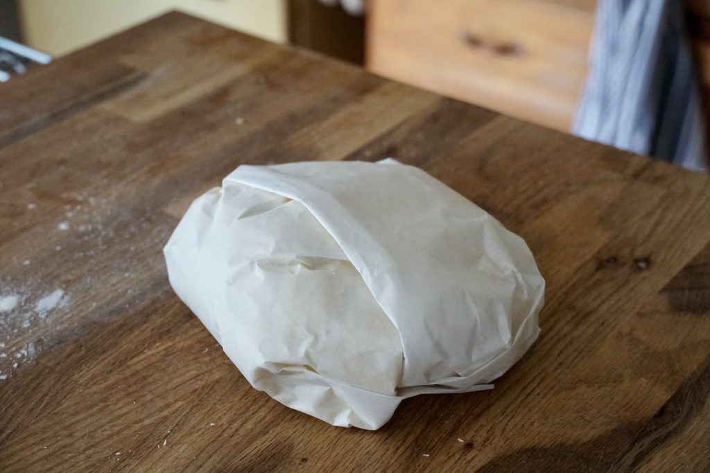 The ball of dough for the flatbreads wrapped in parchment paper.