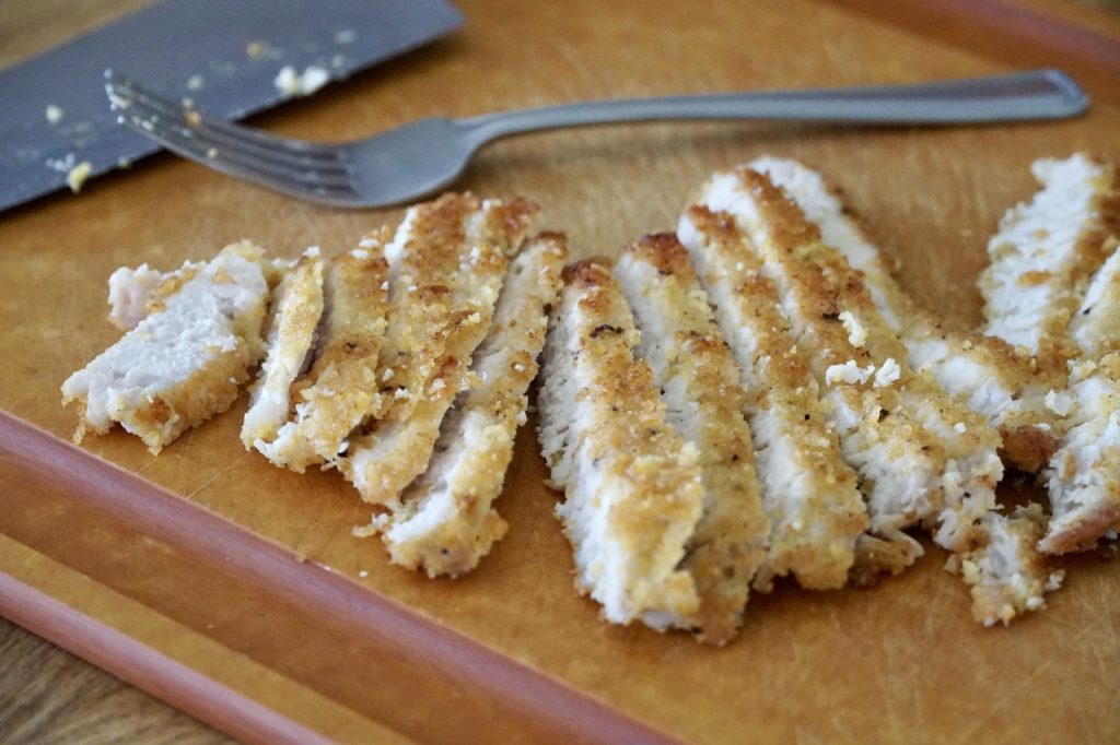A crispy pork cutlet schnitzel, thinly sliced.