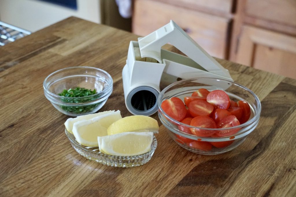 Garnishes for the Crispy pork schnitzel include lemon, cherry tomatoes, chopped parsley and Parmesan cheese.