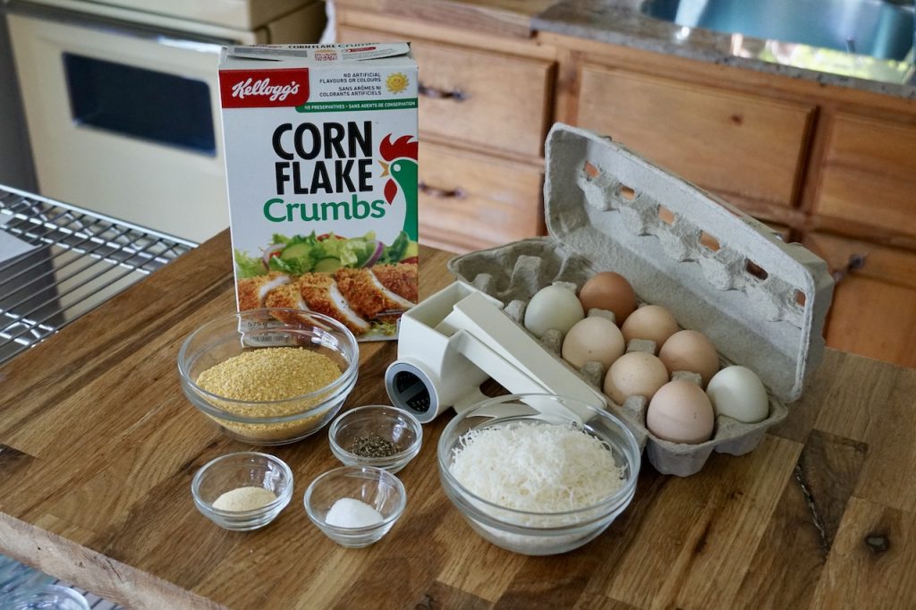 Items needed to bread cutlets include eggs, corn flake crumbs, seasoning and Parmesan cheese.