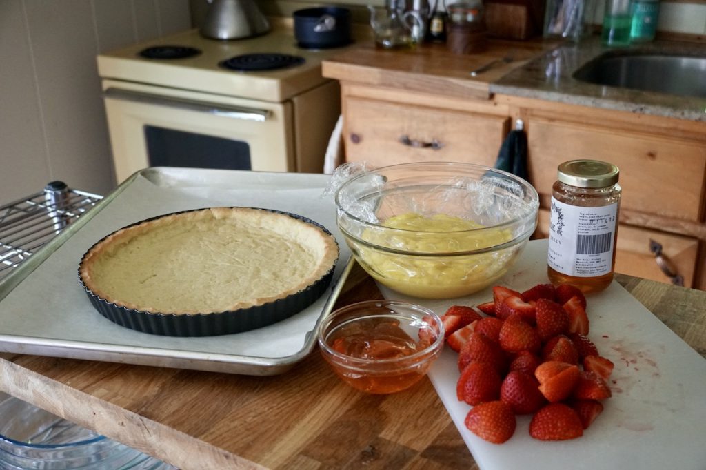 The cooled tart shell, vanilla custard and sliced strawberries.
