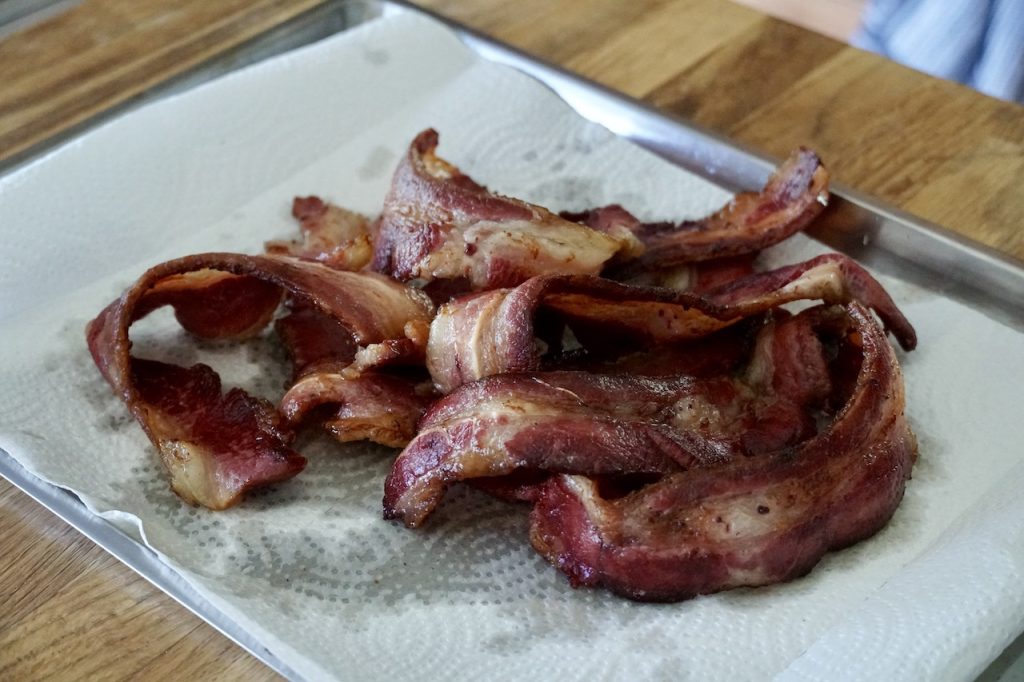 Crispy, freshly cooked thick-cut bacon resting on a plate.