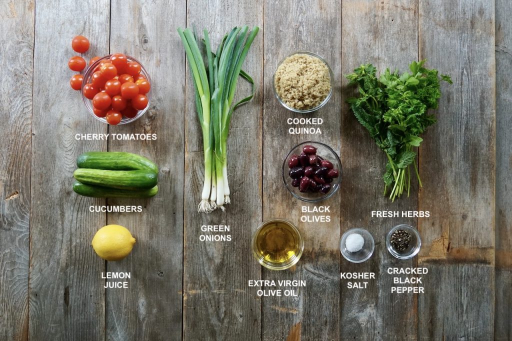 Ingredients needed to make an Easy Summer Salad include tomatoes, cucumbers, green olives, fresh herbs, black olives and a lemony viniagrette.