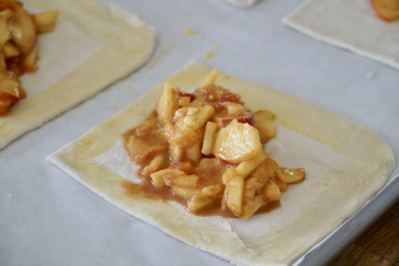 A small square of puff pastry dough filled with the peach mixture, the edges brushed with egg wash.