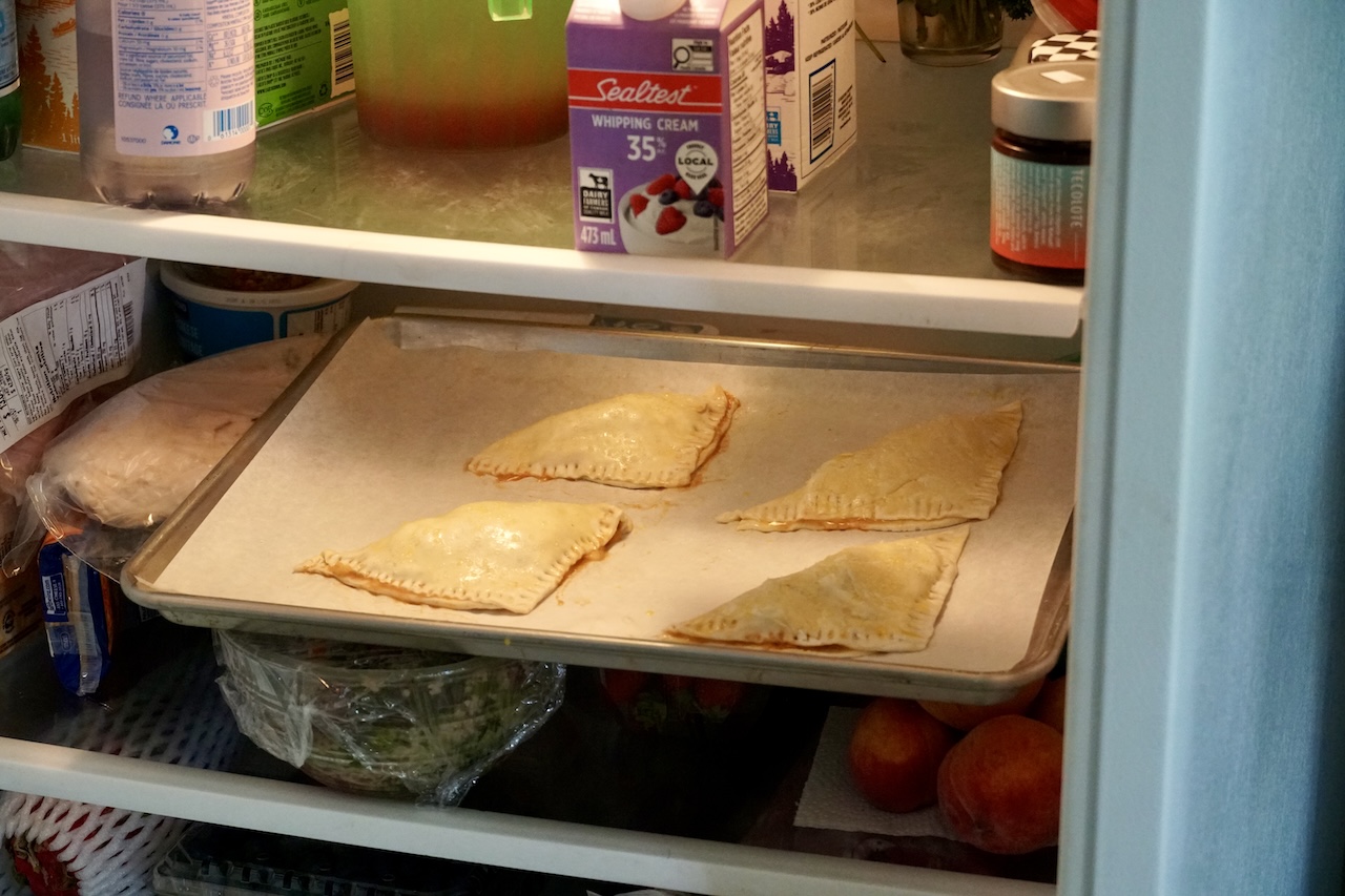 A baking tray of the peach turnovers chilling in the fridge.