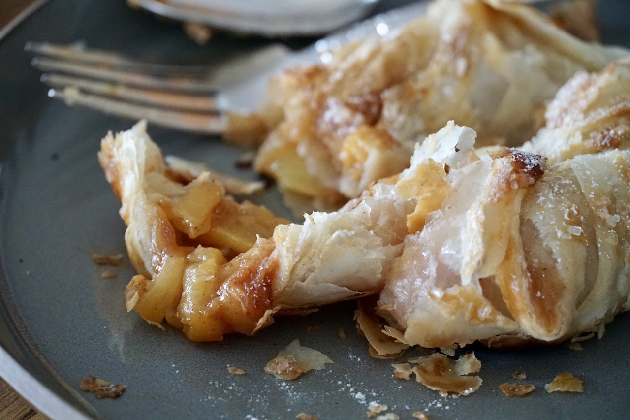 A fresh peach turnovers after being cut open revealing the cooked peach centre surrounded by buttery, flaky puff pastry.