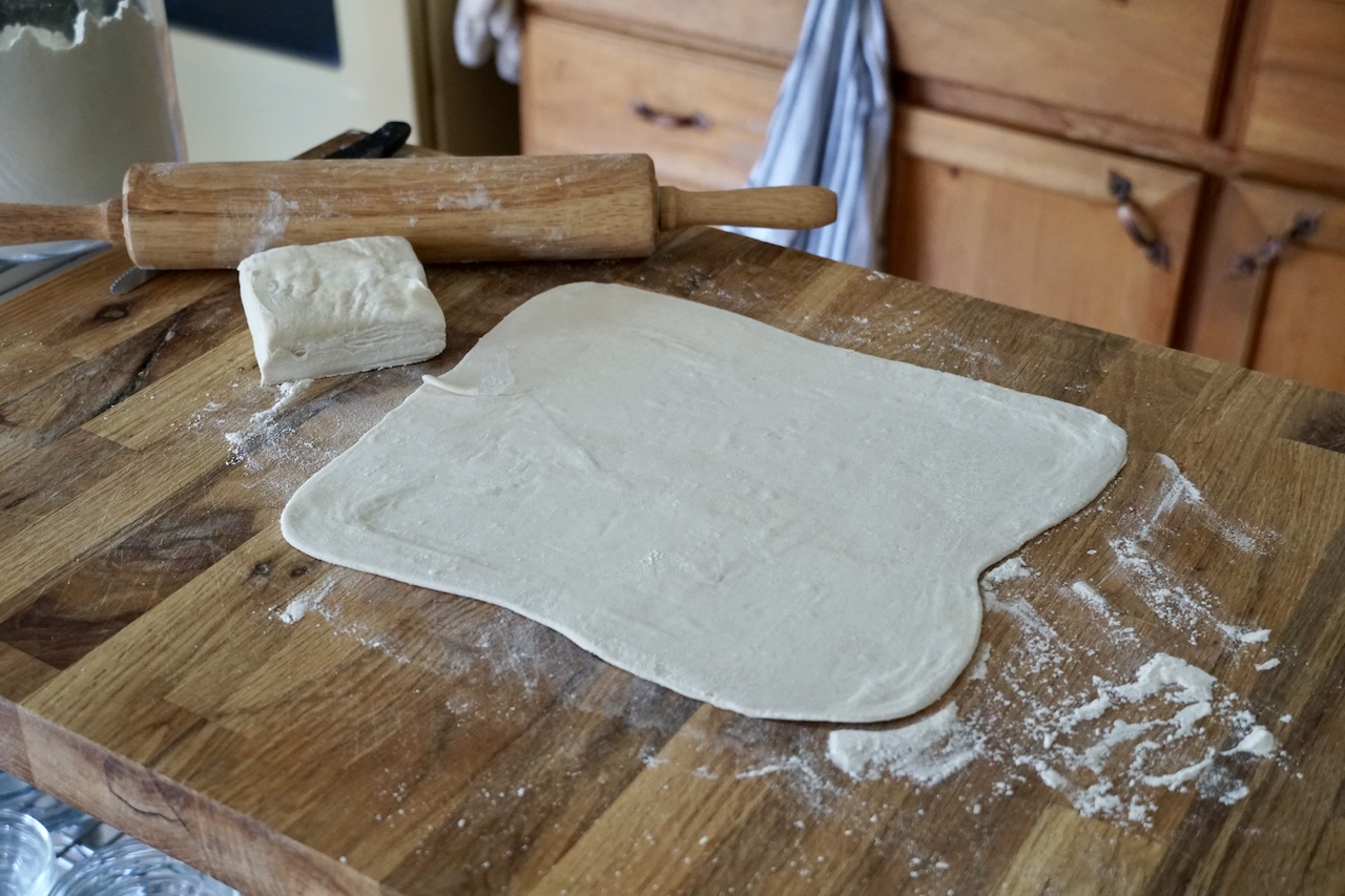 A sheet of puff pastry dough rolled out onto a pastry board.