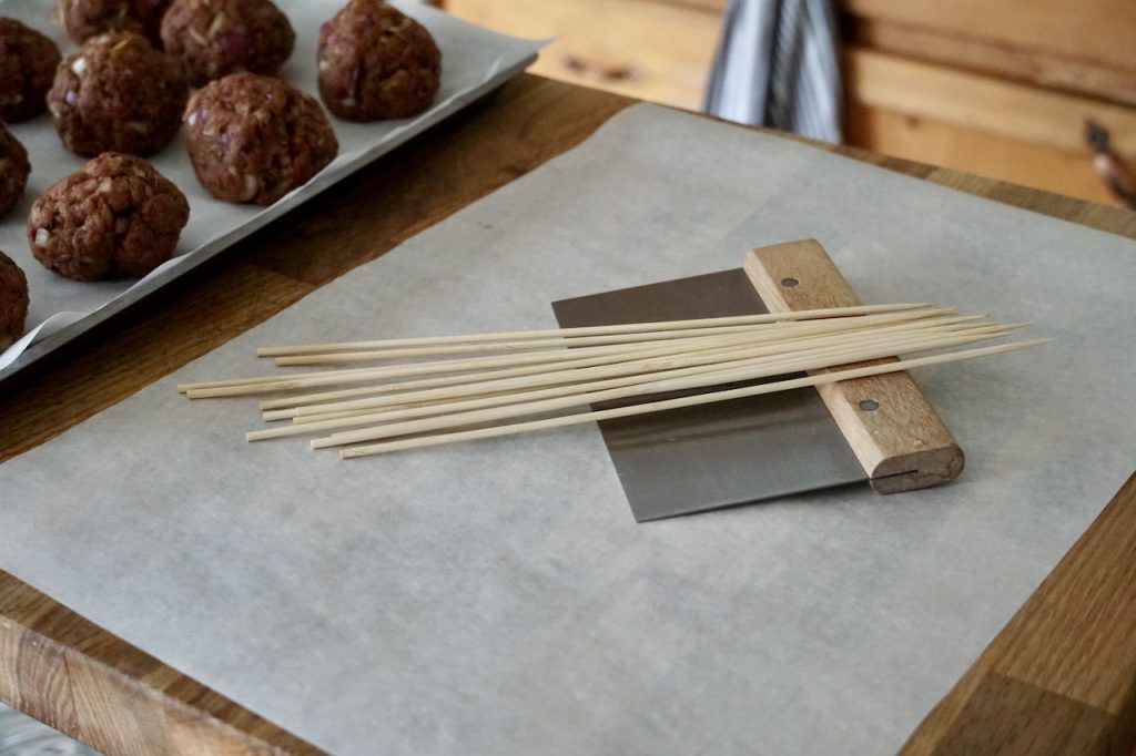 The essential tools needed to create koftas include parchment paper, skewers and a bench scraper.