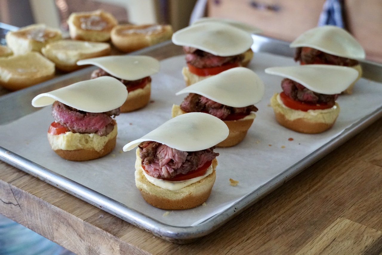 The slices of steak resting on the buns, topped with a slice of provolone cheese.