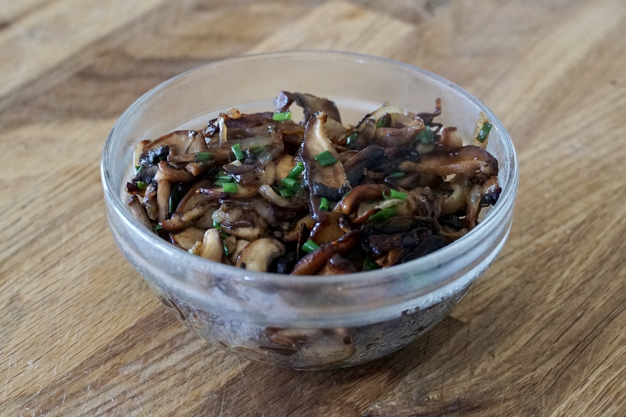 A bowl containing the sautéed mushrooms.