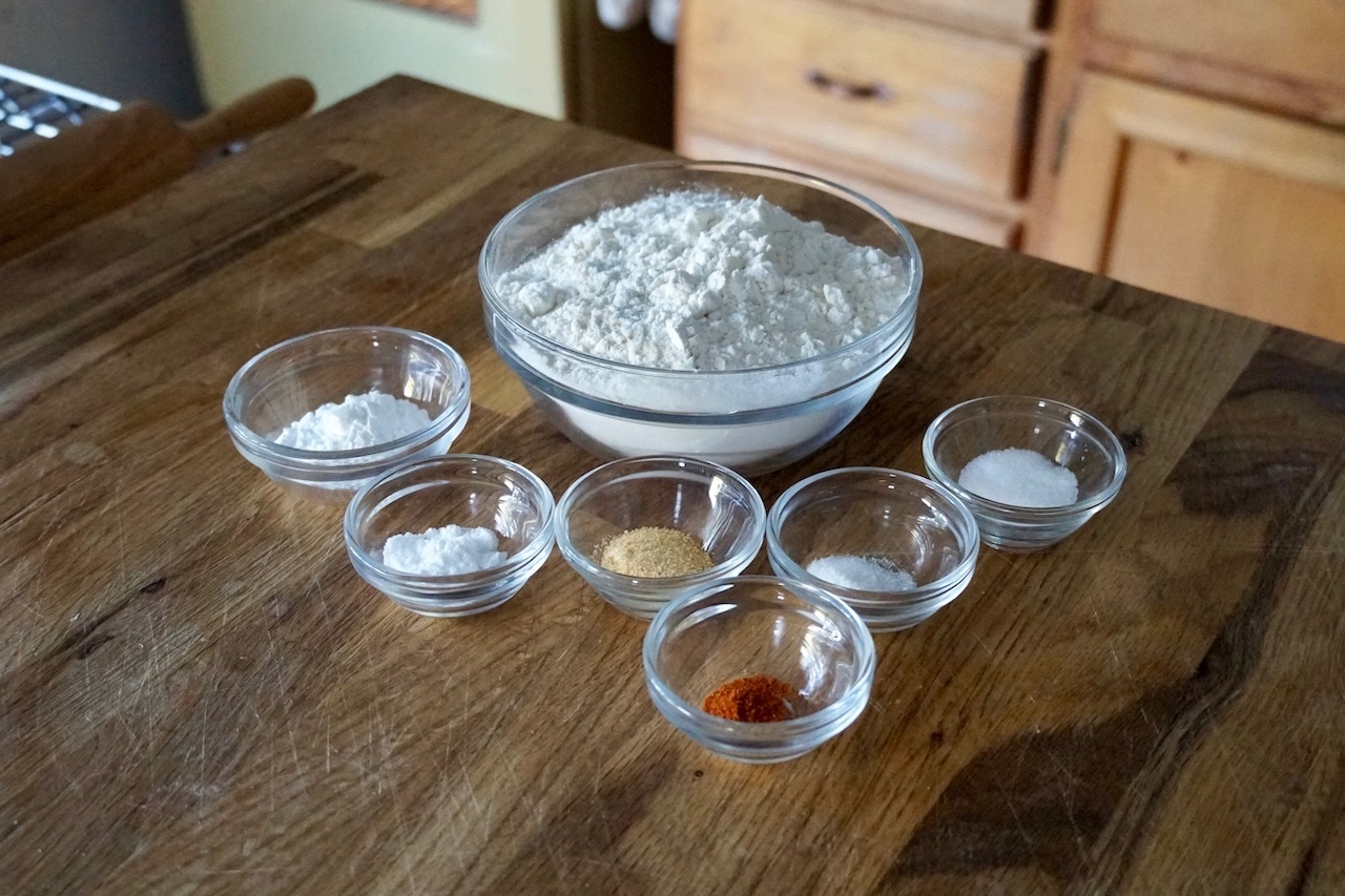 All of the dry ingredients needed to make apple-cheddar biscuits portioned out into small bowls.