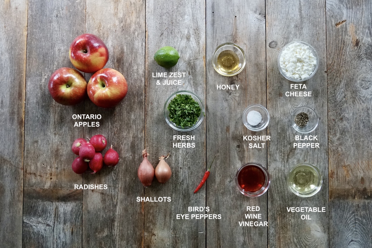 All of the ingredients needed to make the apple salad laid out on a large board.