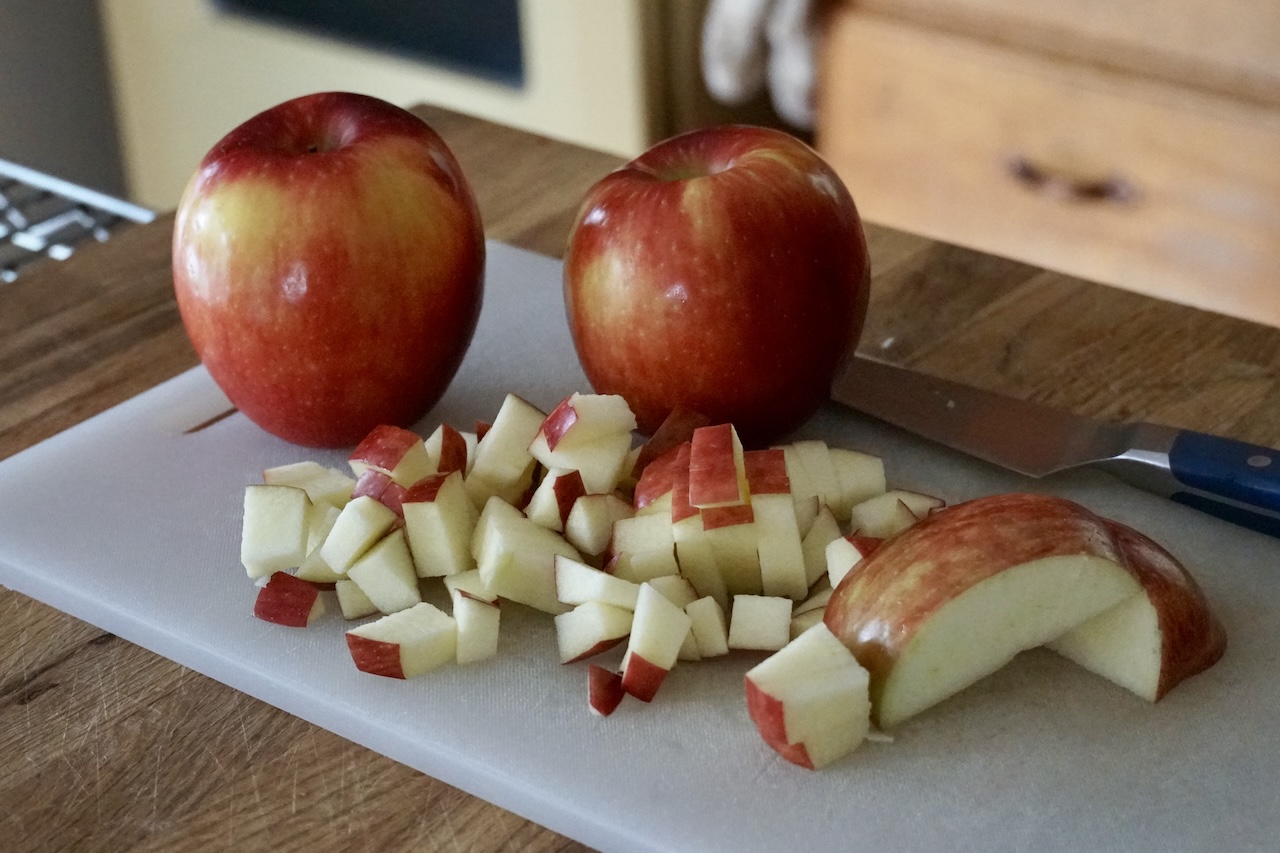 A cutting board topped with two Ontario Honeycrisp apples plus more apples cut into chunks.