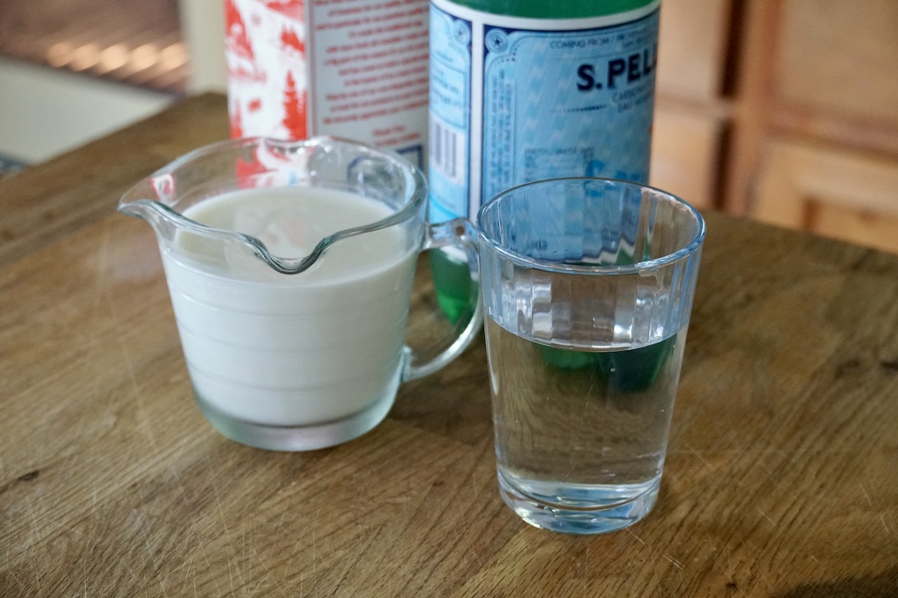 A measure of whole milk and a glass of sparkling water.