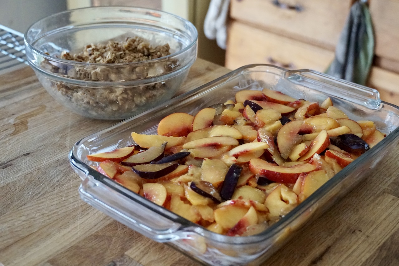 The fresh tender fruit or stone fruit spilled into a buttered casserole dish.