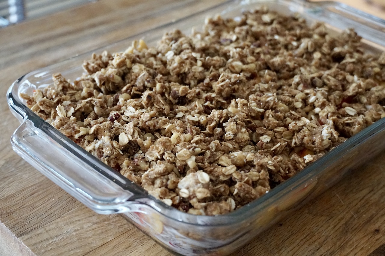 The fresh fruit crisp assembled in a glass casserole dish, ready for the oven.