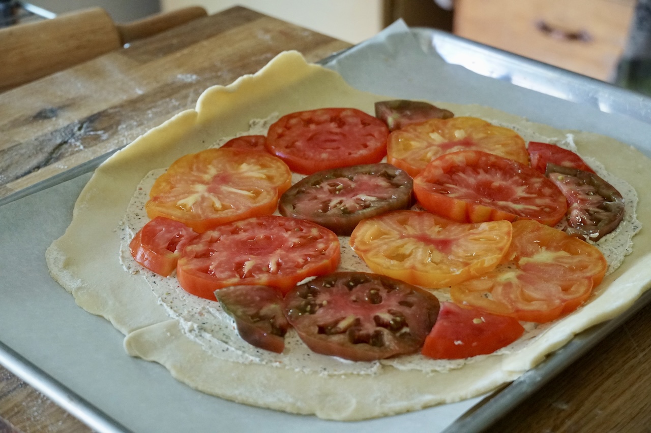 The pastry dough smeared with herbed cream cheese then topped with tomato slices.