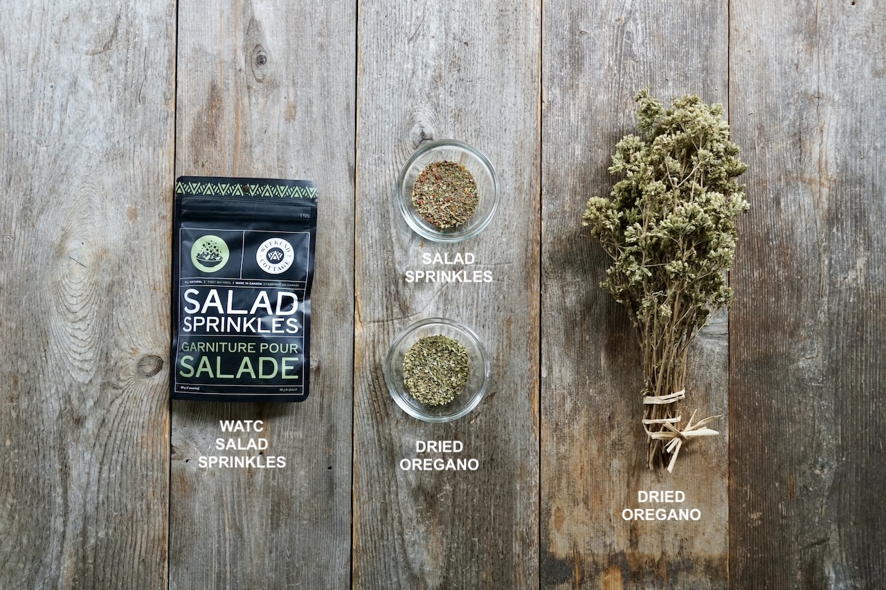 Two options for dried seasoning displayed on a wooden board include oregano or salad sprinkles.