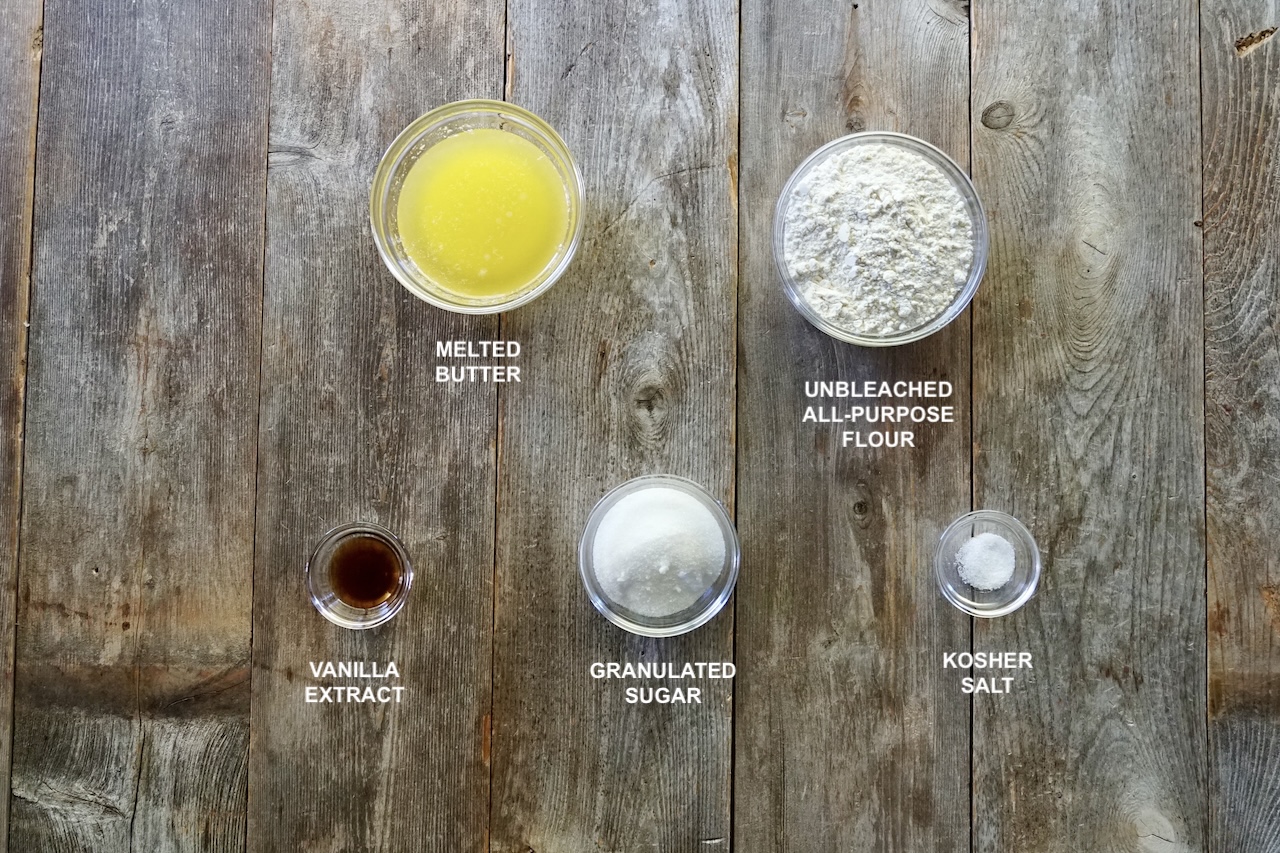 Ingredients for the shortbread base, assembled in small bowls include: melted butter, granulated sugar, vanilla extract, flour and kosher salt.