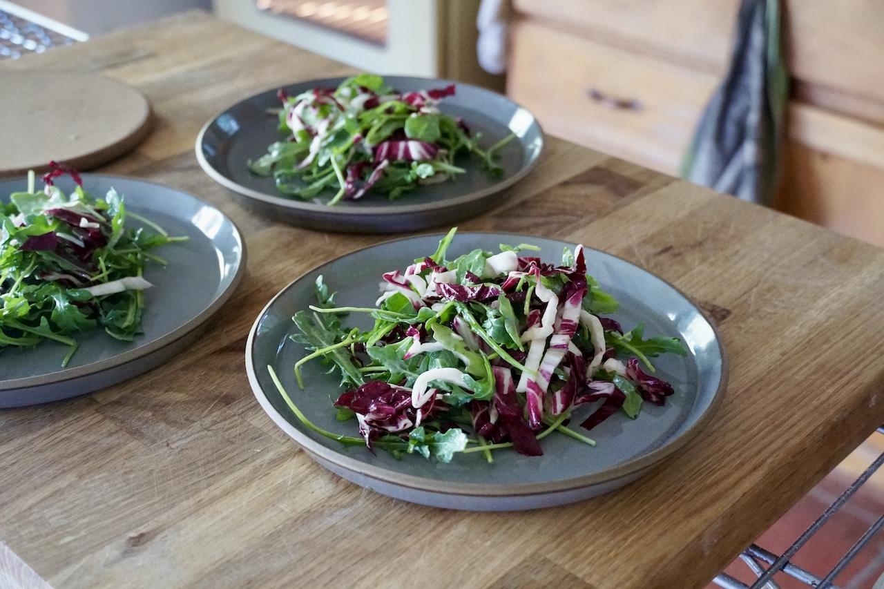 Side plates filled with tossed radicchio and arugula.