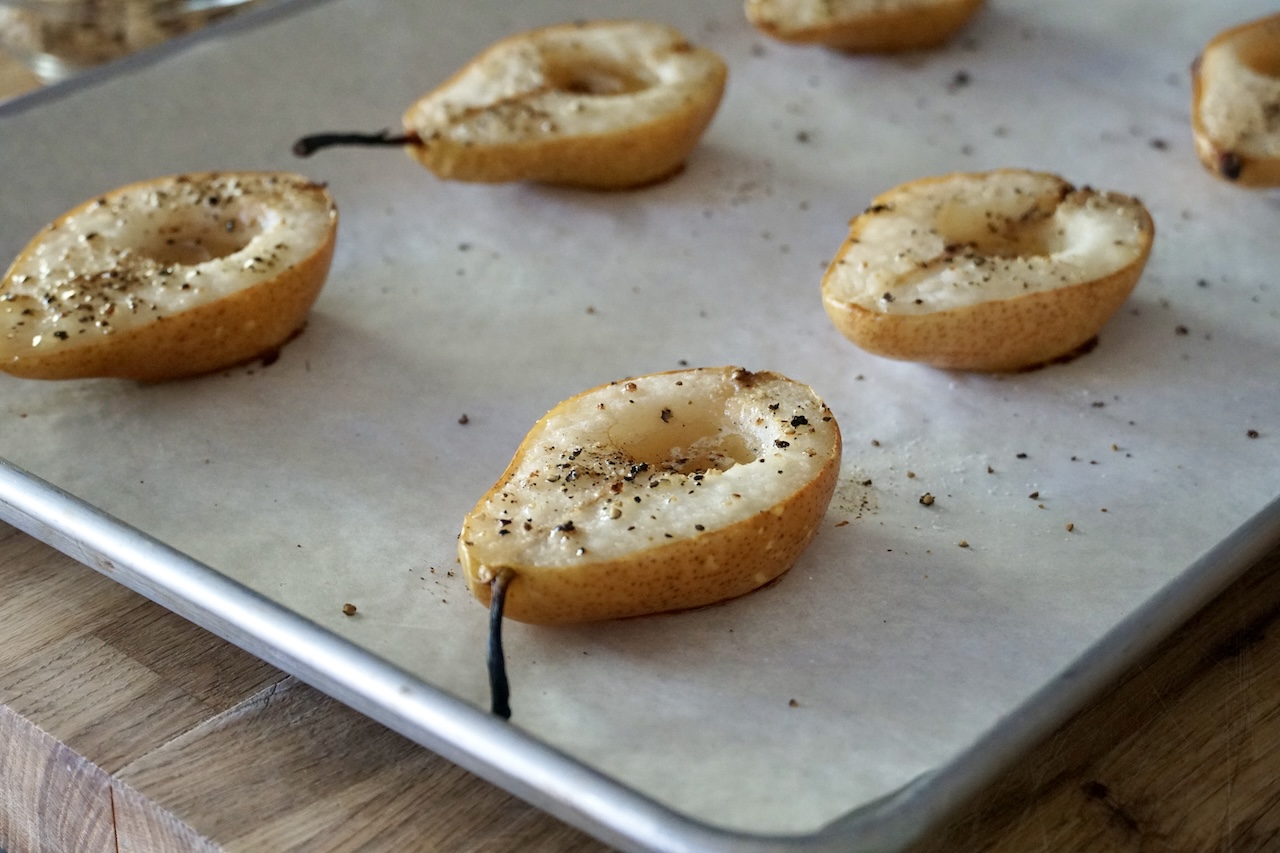 Roasted pears resting on a baking tray.