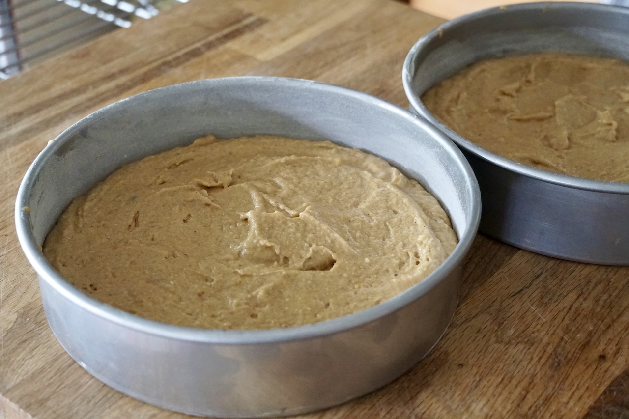 Spiced pumpkin cake divided between two round cake pans.
