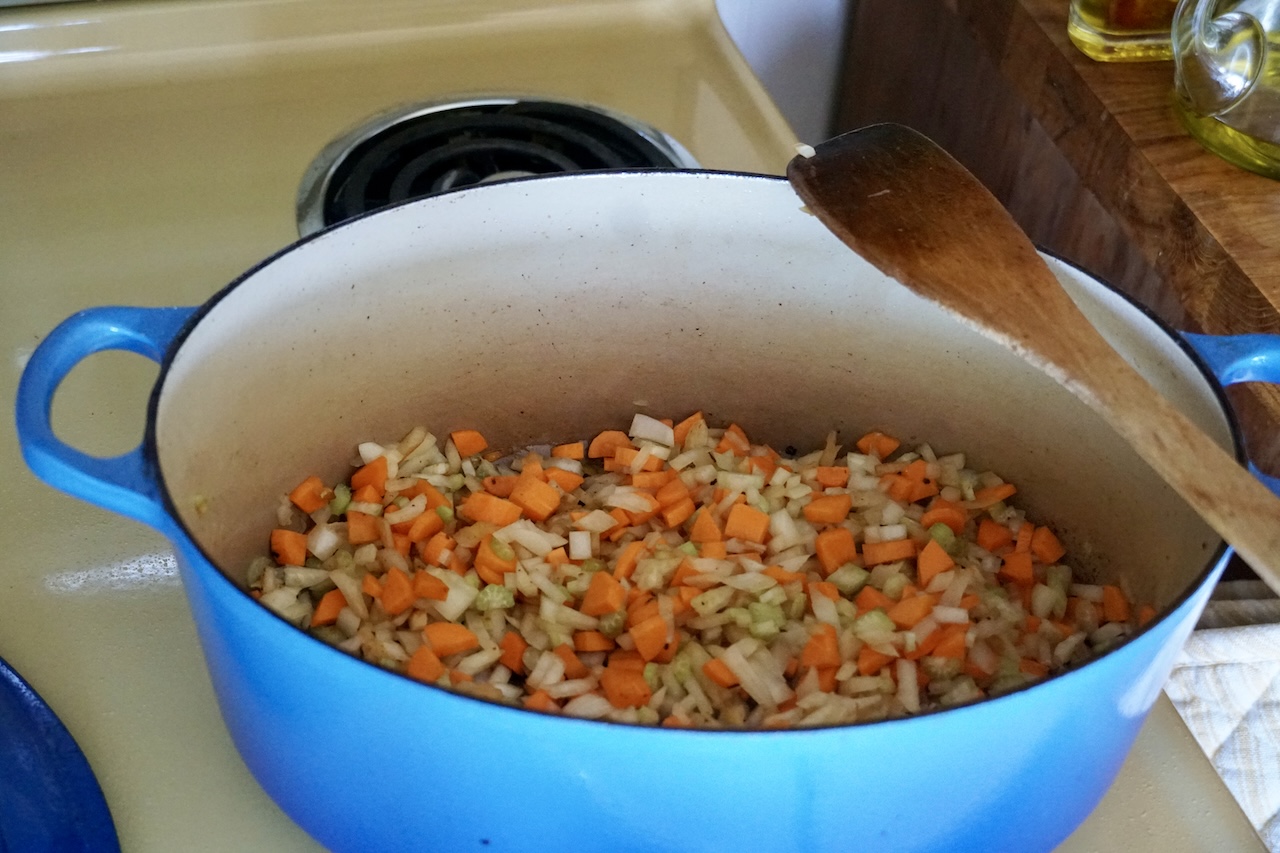 The stew pot with the mirepoix of carrot, onion and celery cooking within.