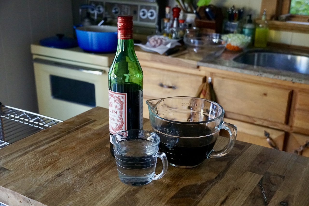 The liquids for the stew including the red vermouth, mushrooms juice and water.